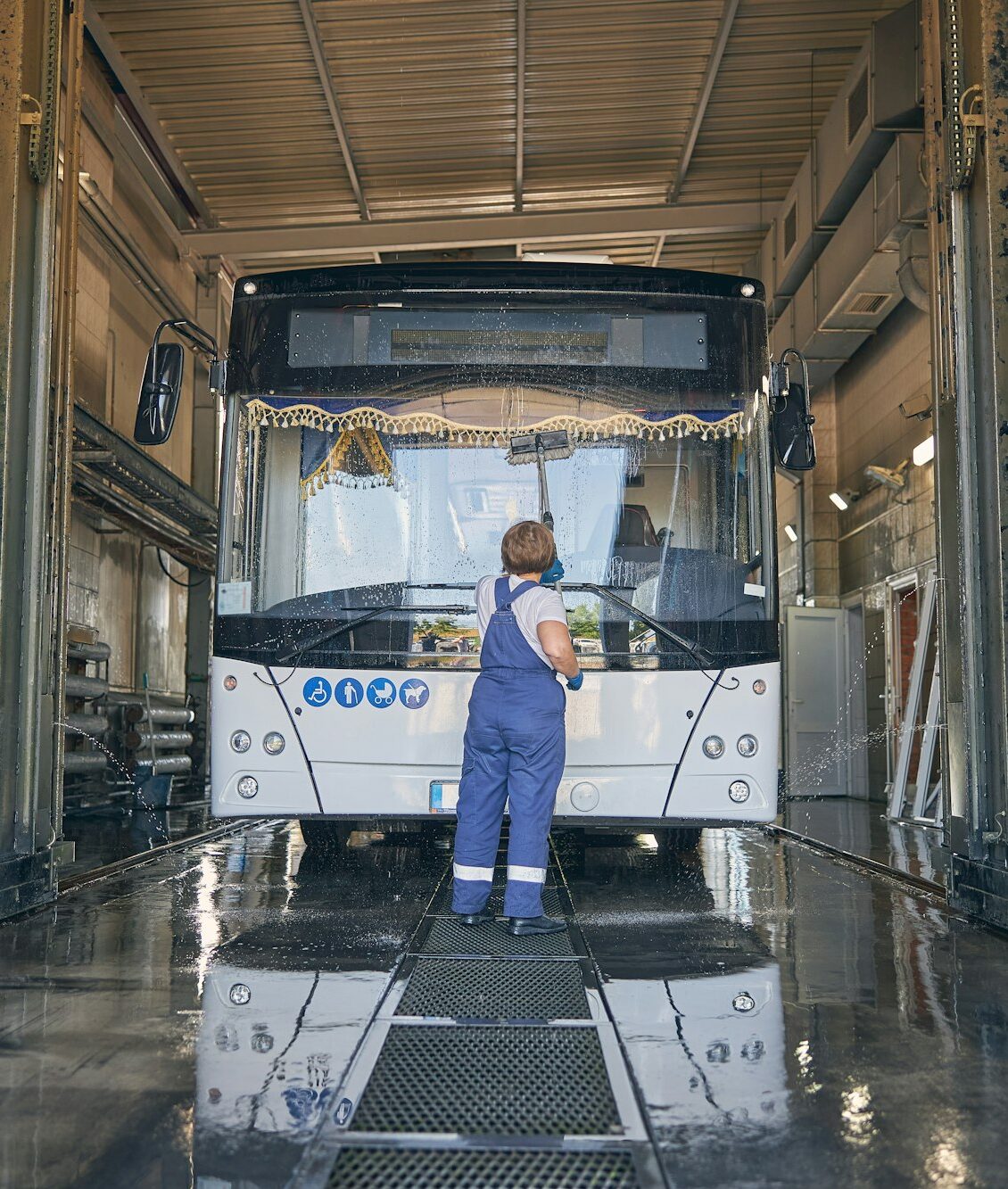Concentrated woman wiping glass on big bus