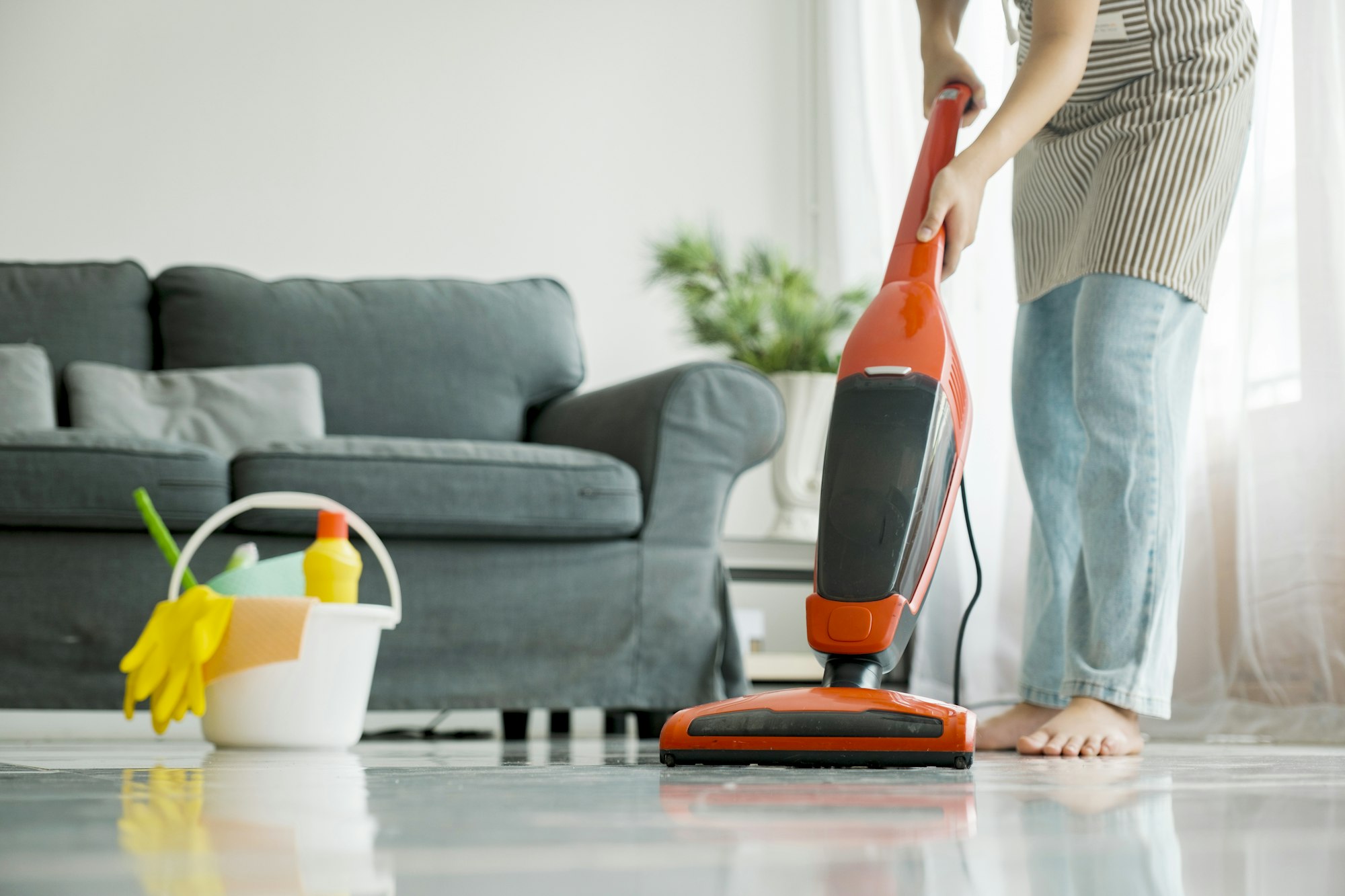 Young woman cleaning house with vacuum cleaner.